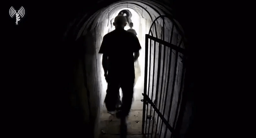 a man is walking through a dark tunnel with a light at the end
