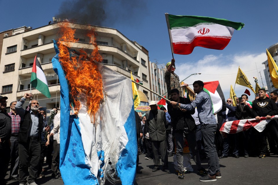 a group of people holding flags including one that says ' iran ' on it