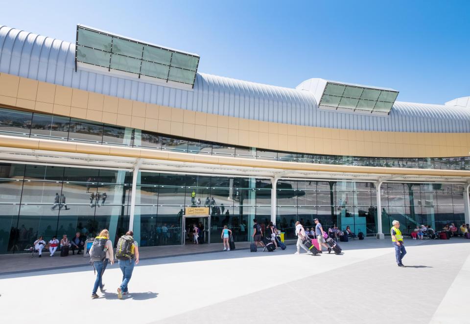 people walking in front of a building with a yellow sign that says arrivals