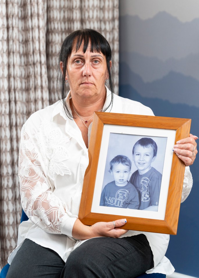 a woman is holding a framed picture of two children one of whom is wearing a shirt that says monkey