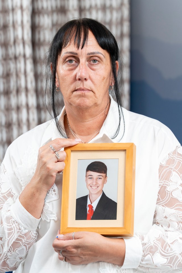 a woman holds a picture of a young man in a suit and tie