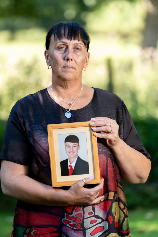 a woman holds a picture of a young man in a suit and tie