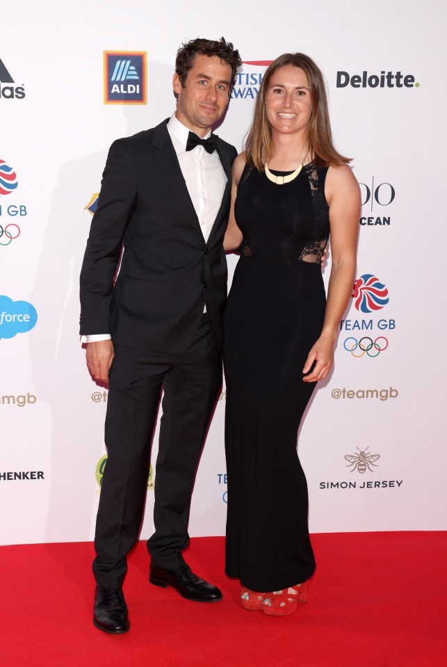 a man and a woman pose on a red carpet sponsored by aldi and deloitte