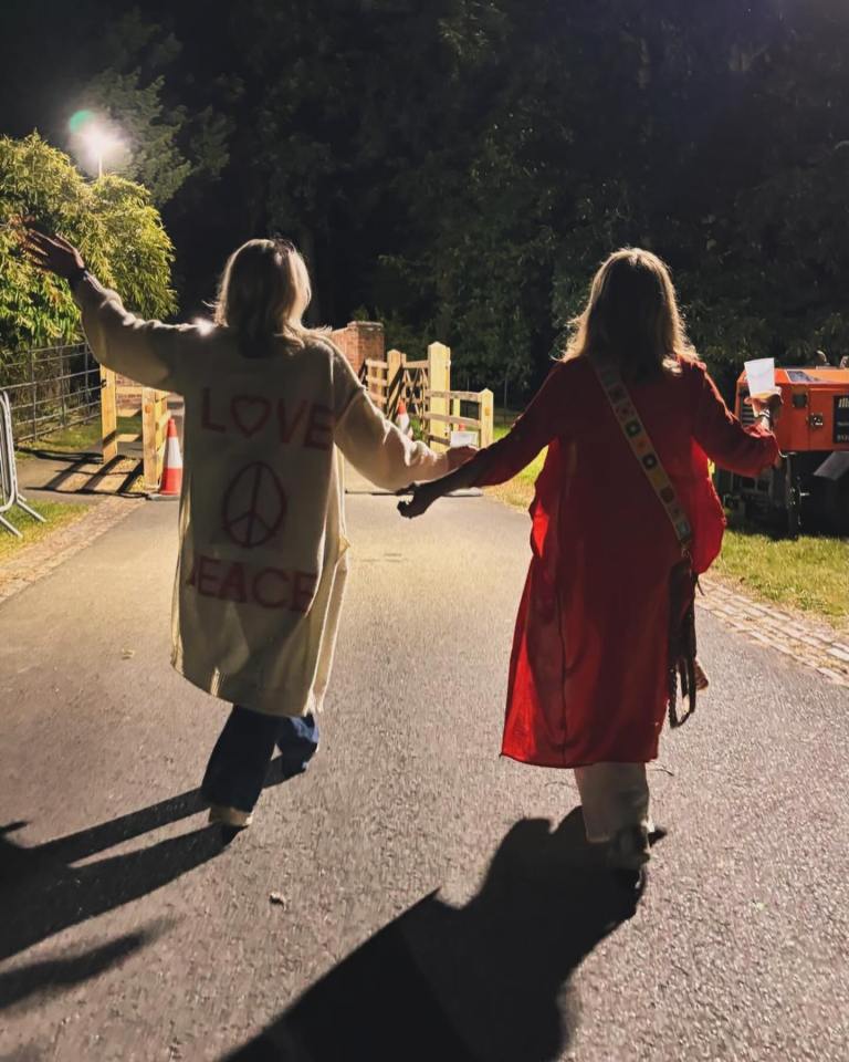 two women walking down a road with one wearing a jacket that says love peace