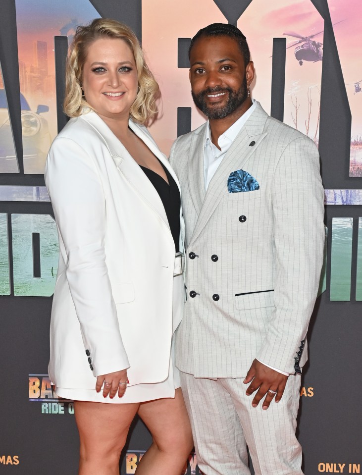 a man and a woman pose on a red carpet in front of a sign that says only in