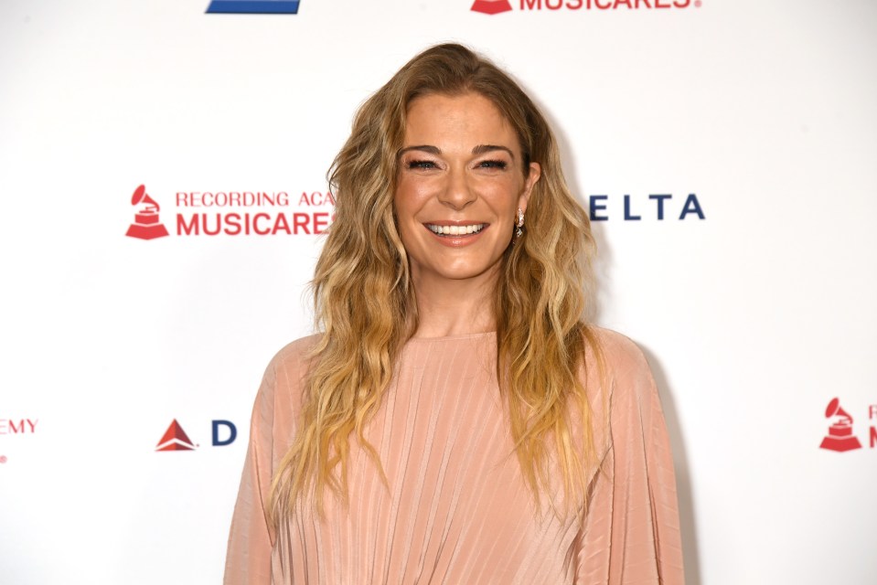 a woman smiles in front of a recording academy musiccare sign