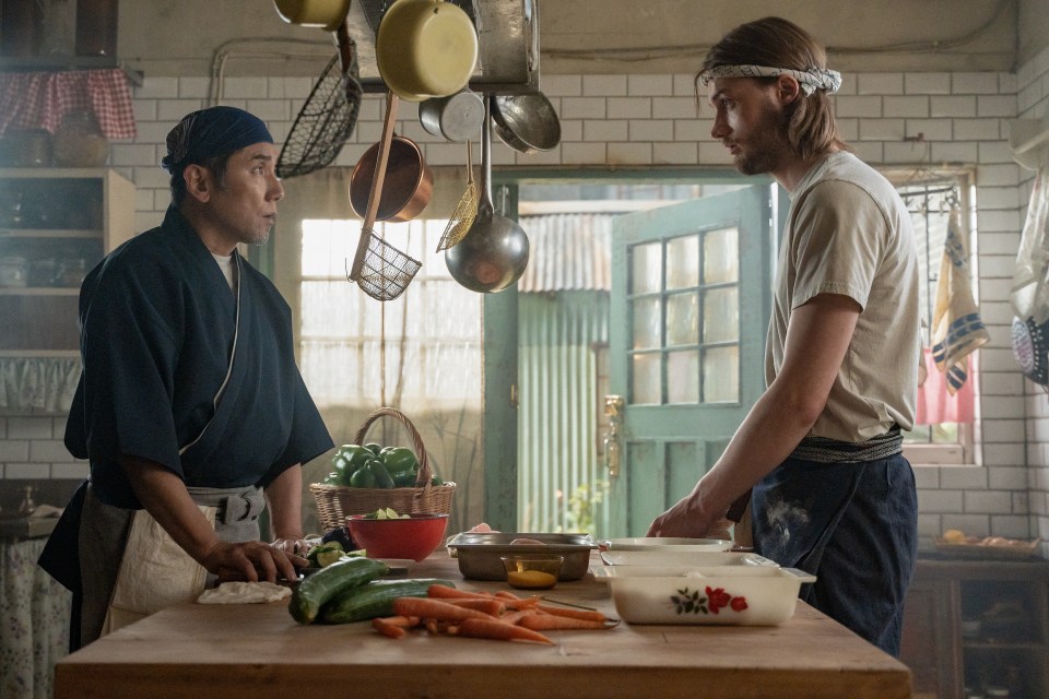 two men are standing in a kitchen preparing food