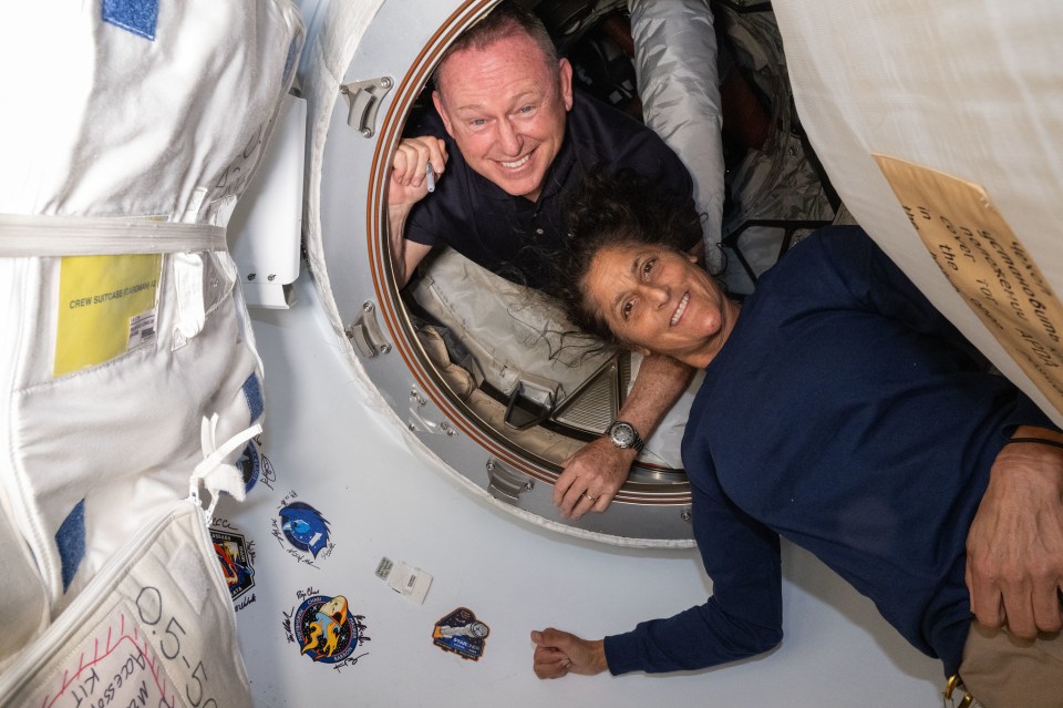 a man and a woman are looking out of a space shuttle window
