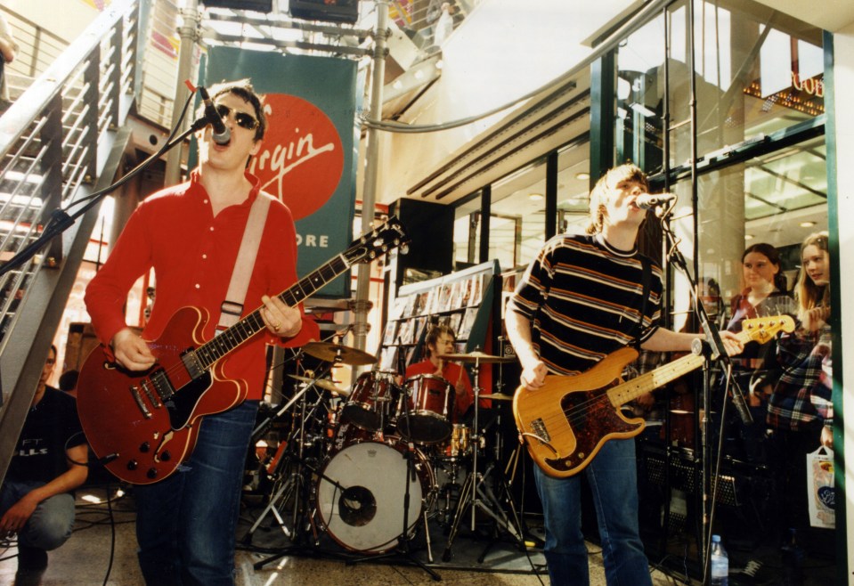 a band performs in front of a virgin store sign