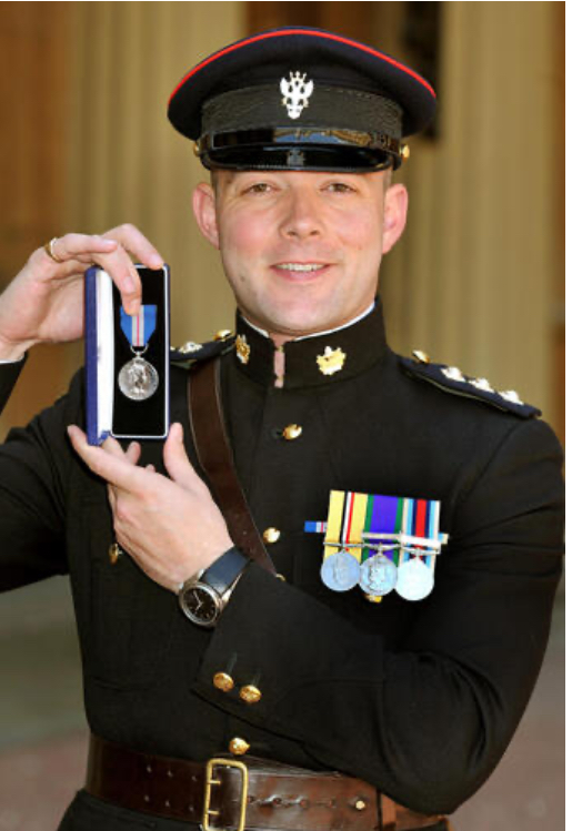 a man in a military uniform holds up a medal