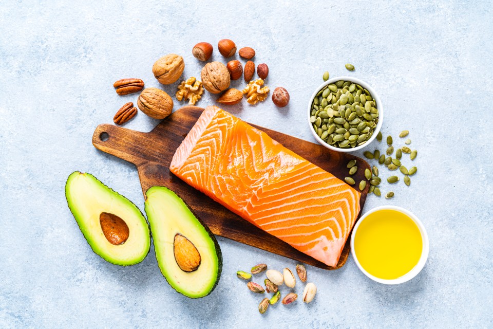 a piece of salmon is on a cutting board surrounded by nuts and seeds
