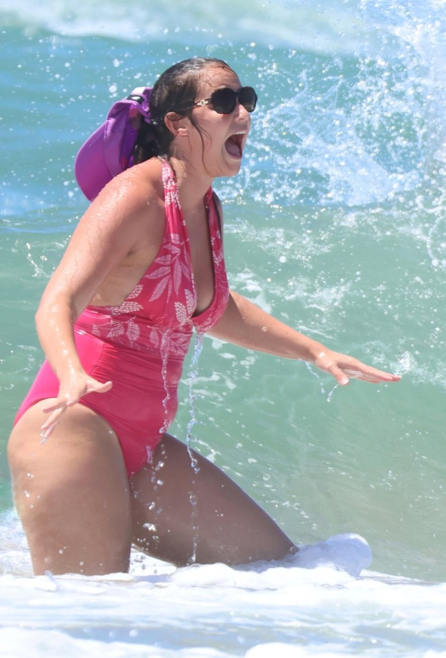 a woman in a pink swimsuit is splashing in the ocean