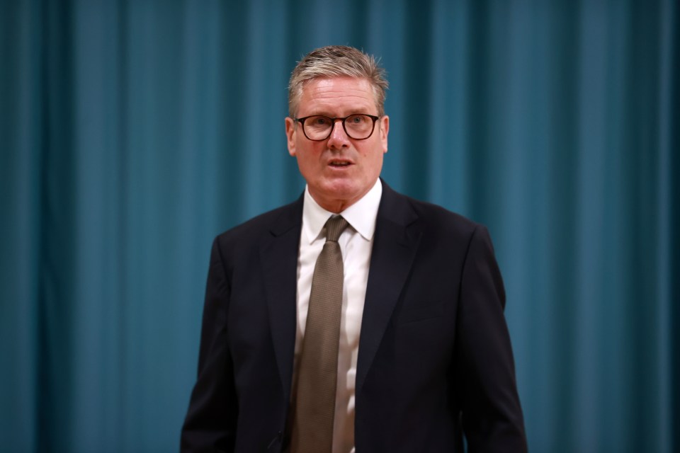a man in a suit and tie stands in front of a blue curtain