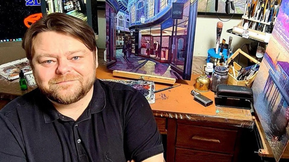 a man with a beard stands in front of a painting with the number 21 on it