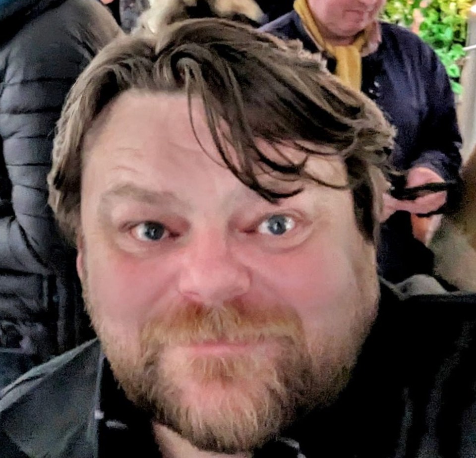 a man with a beard and blue eyes looks at the camera