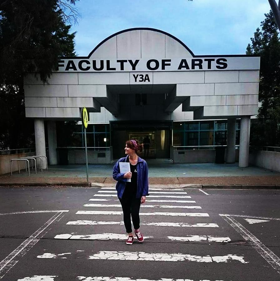 a woman crosses the street in front of the faculty of arts