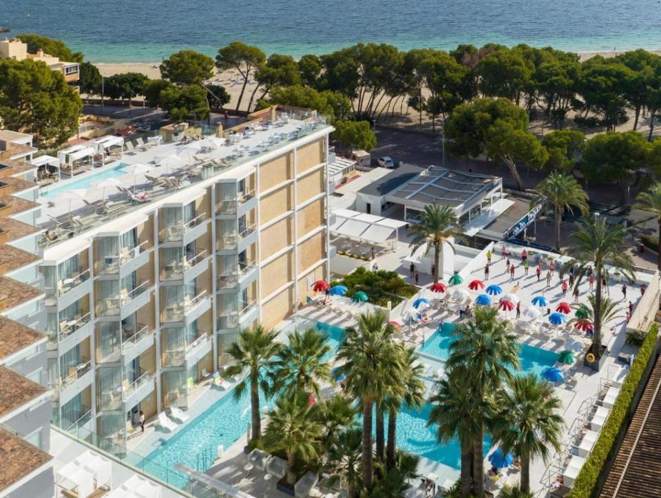 an aerial view of a hotel with a large pool and palm trees