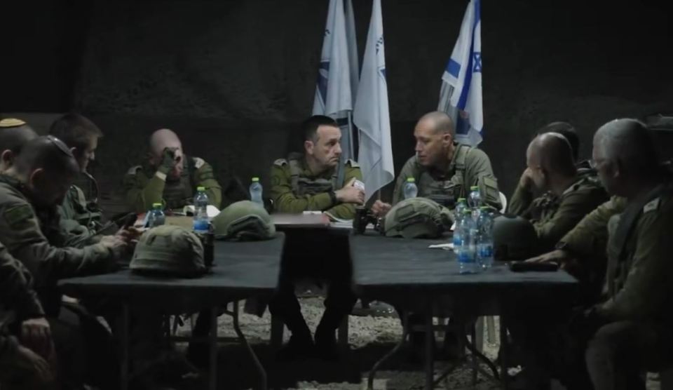 a group of soldiers sit around a table with bottles of water