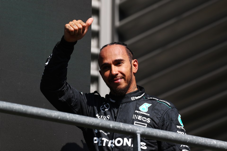 a man in a petronas jacket giving a thumbs up