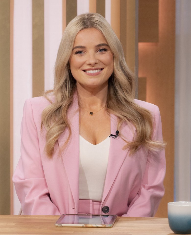 a woman in a pink jacket sits at a table