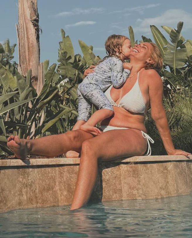 a woman in a bikini sits next to a child in a pool