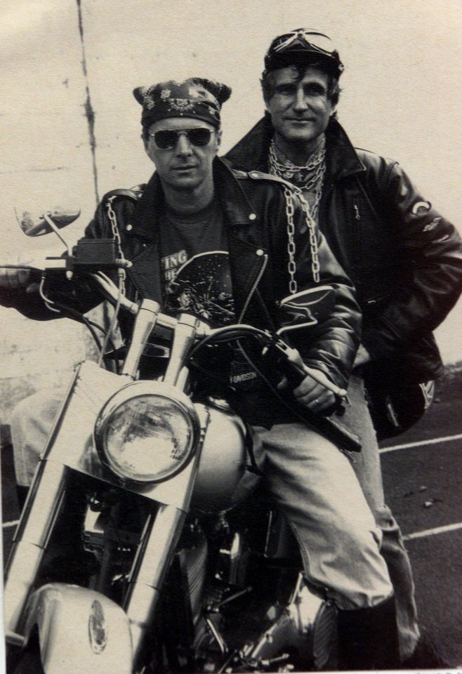 a man wearing a t-shirt that says ing on it sits on a motorcycle