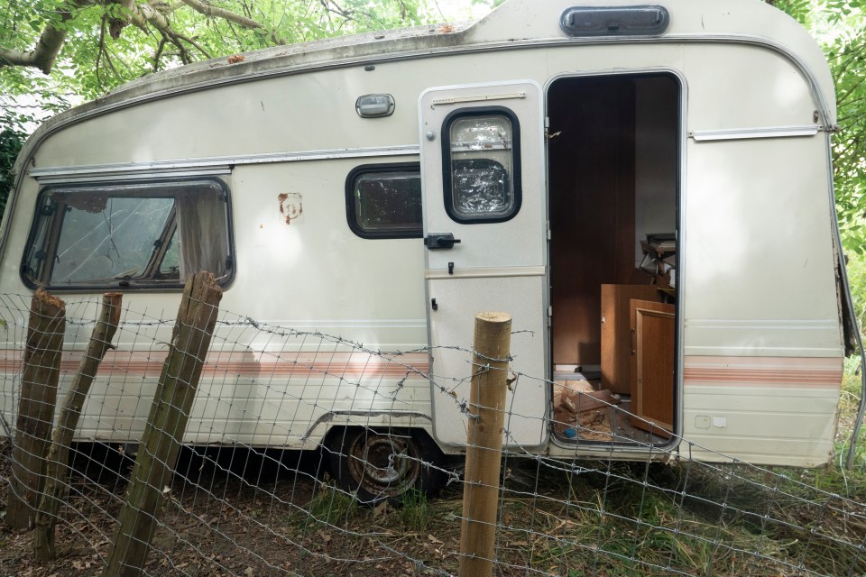 a white camper is behind a barbed wire fence