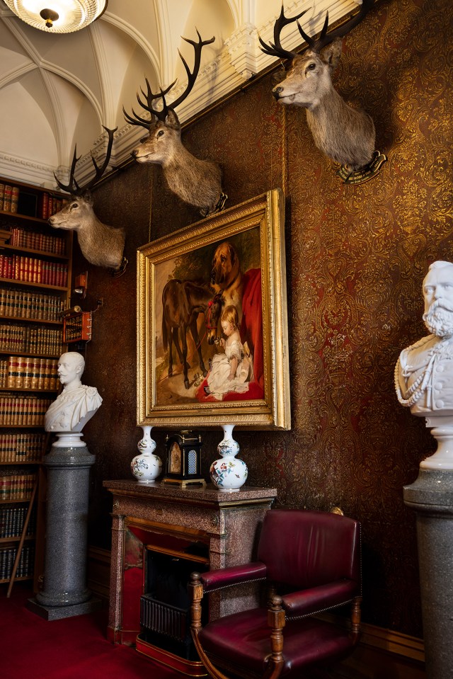 a painting of a deer and a dog hangs above a fireplace