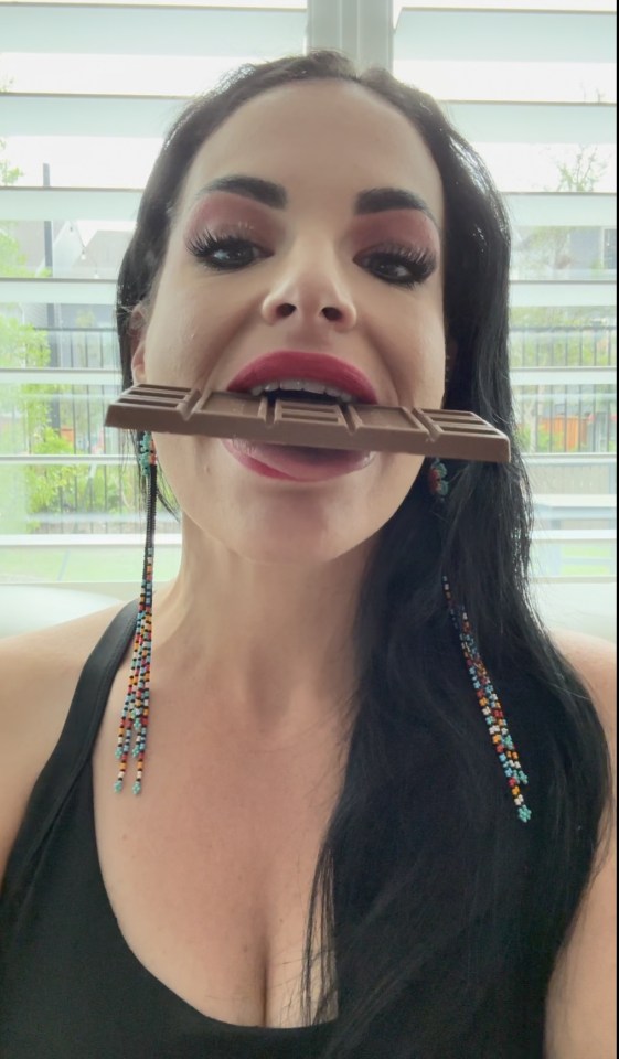 a woman with a bar of chocolate in her mouth