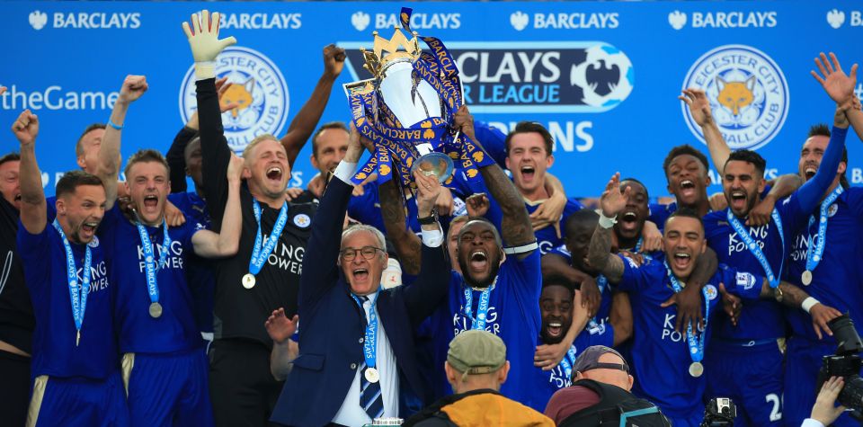 a group of soccer players holding up a trophy that says barclays on it