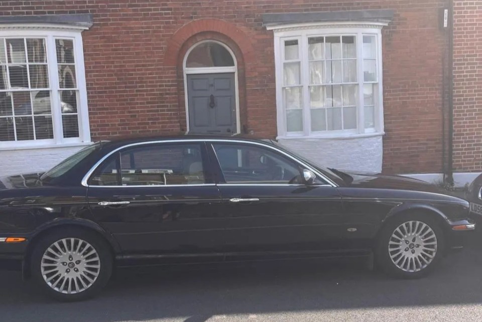 a black car is parked in front of a brick building