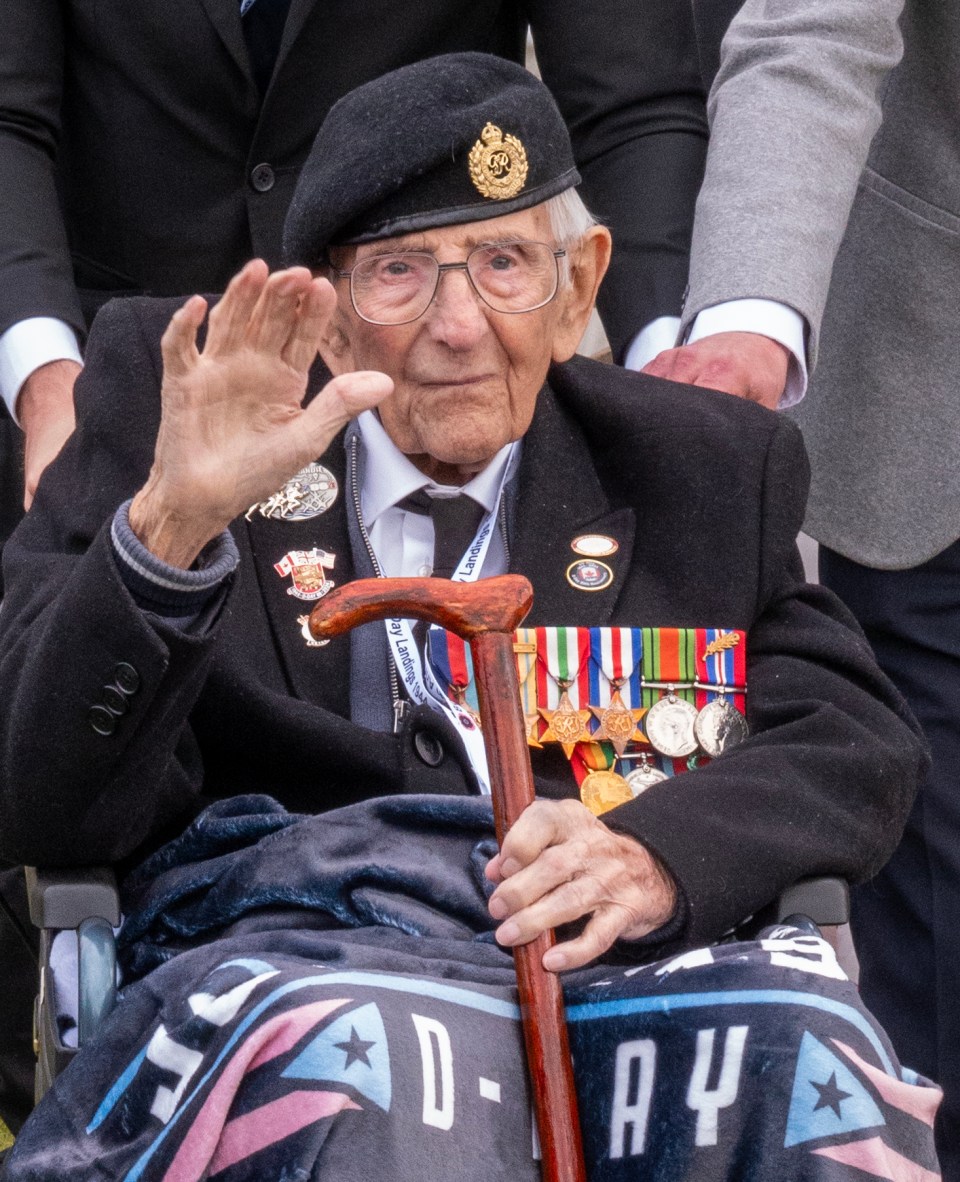 a man in a wheelchair with a cane and a blanket that says d-day