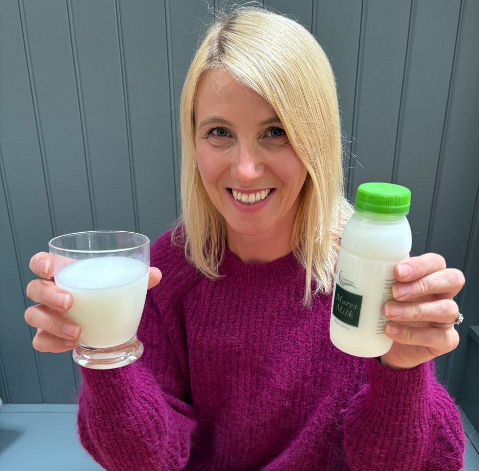 a woman in a purple sweater is holding a glass of milk and a bottle of milk