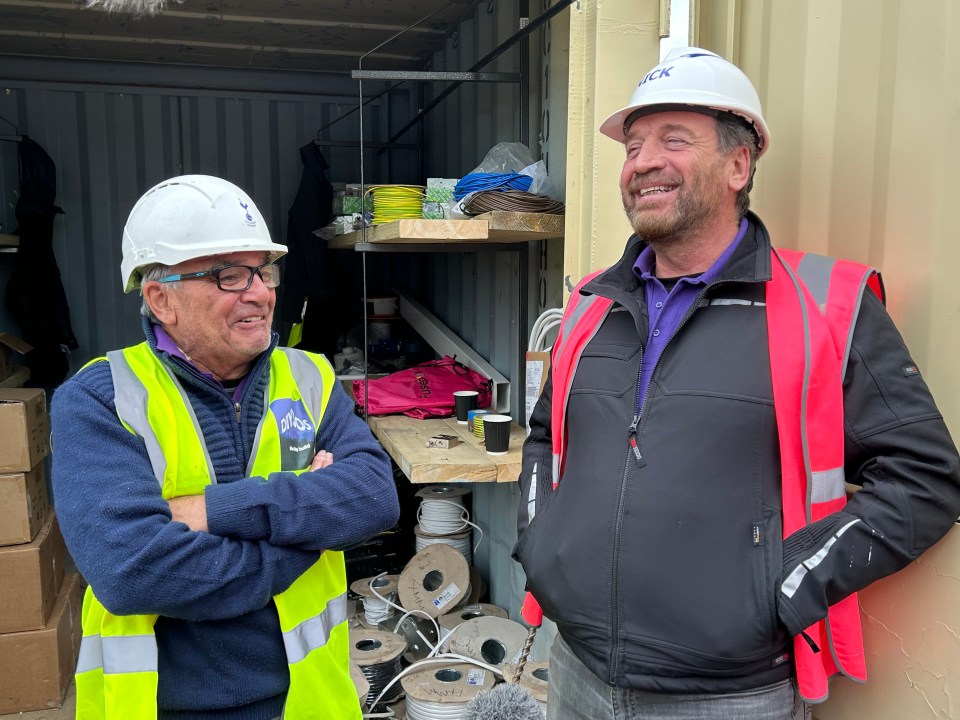 two men wearing hard hats and safety vests are standing next to each other