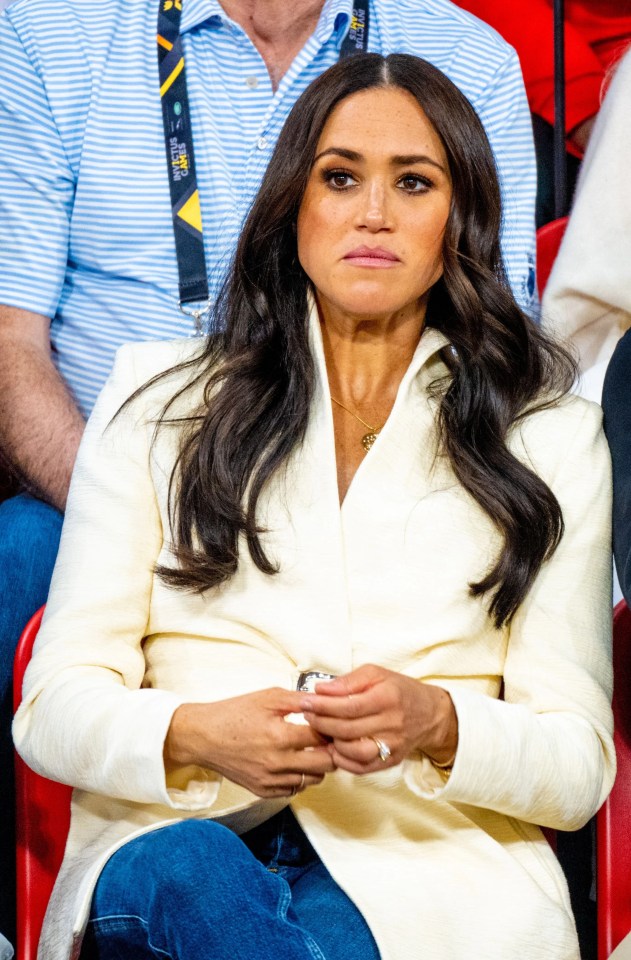 a woman in a white jacket sits in a stadium watching a game