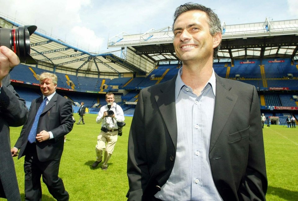 a man in a suit is smiling in front of a stadium that says fly emirates