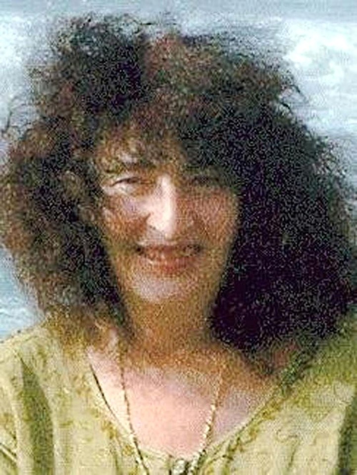 a woman with curly hair is smiling and wearing a green shirt .
