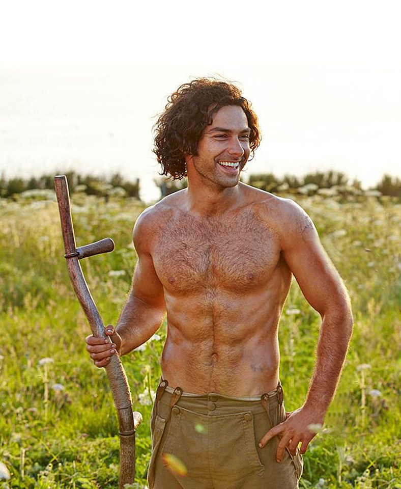 a shirtless man holding a wooden stick in a field