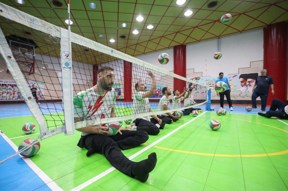 a group of men are playing volleyball in a gym
