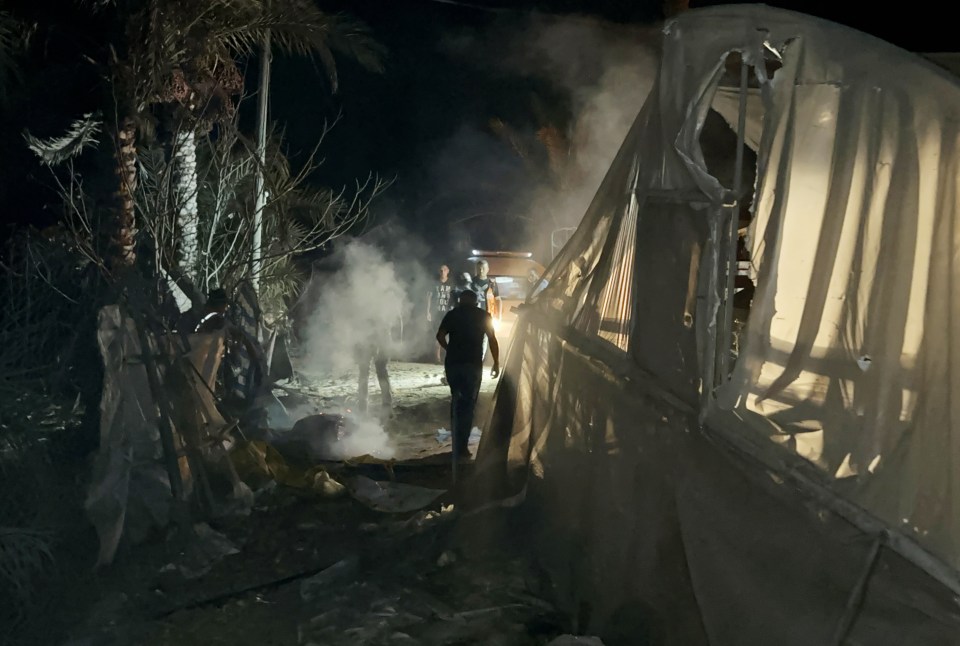 a group of people standing in front of a tent with smoke coming out of it