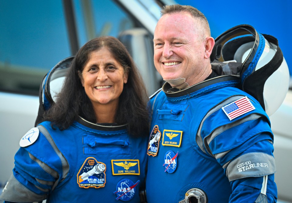 a man and a woman wearing nasa space suits pose for a picture