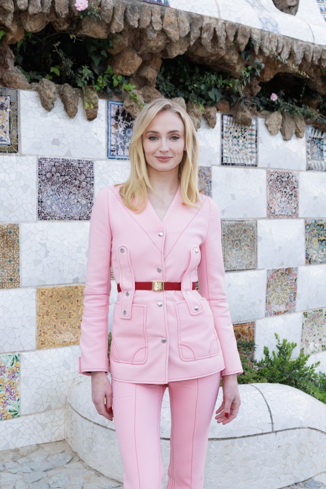 a woman in a pink suit stands in front of a wall