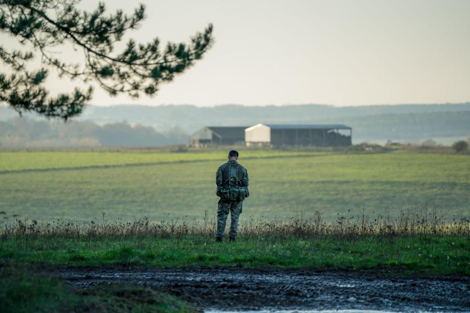 a man standing in a field with a white building in the background