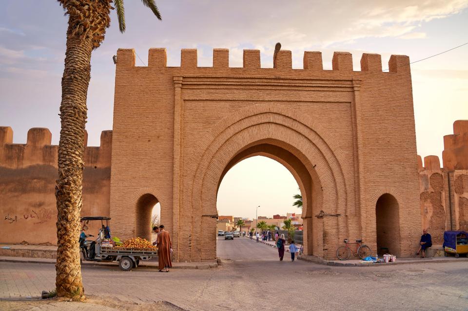 a brick archway with a palm tree in front of it