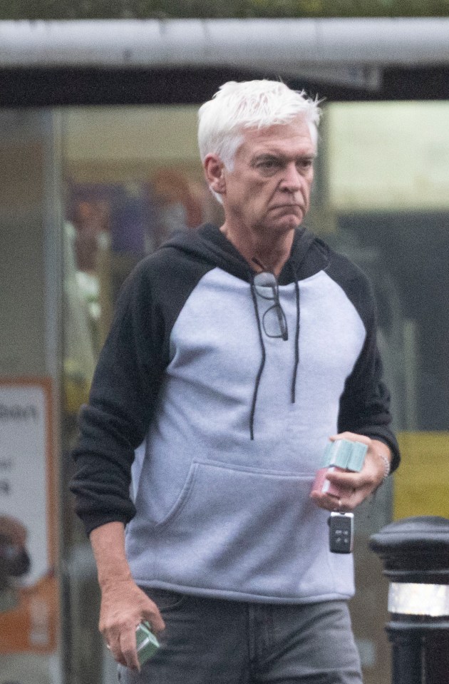 a man in a grey and black hoodie holds a cell phone