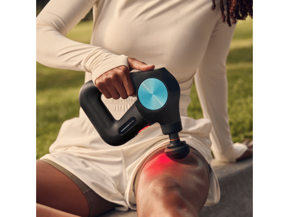 a person is using a theragun device on their knee