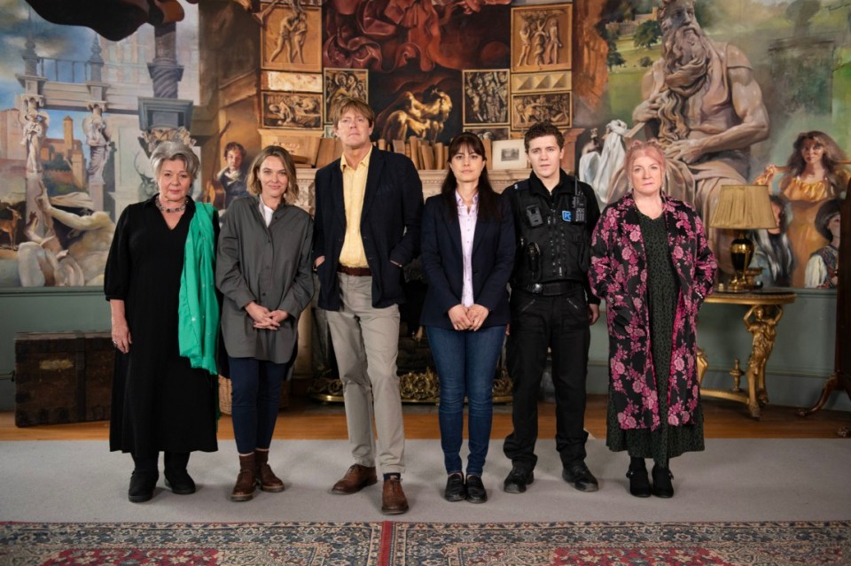 a group of people standing in front of a wall with paintings on it