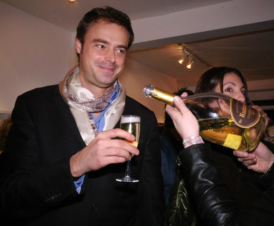 a man in a suit is holding a bottle of champagne