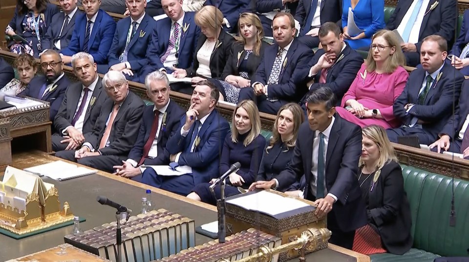 a man in a suit stands in front of a group of people in suits and ties