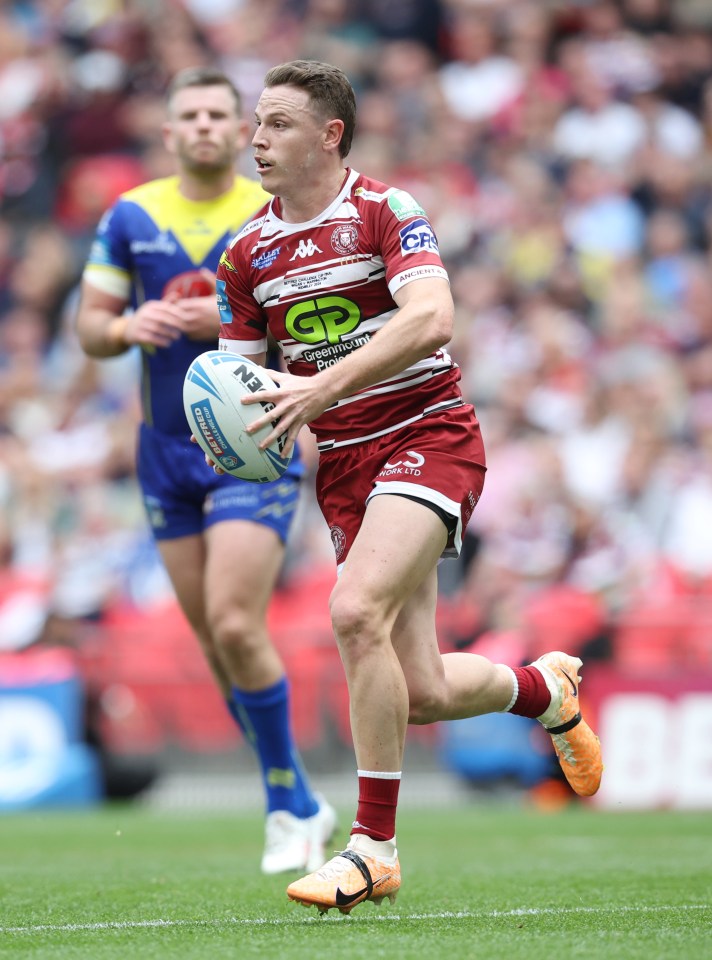 a man in a gp jersey runs with a rugby ball